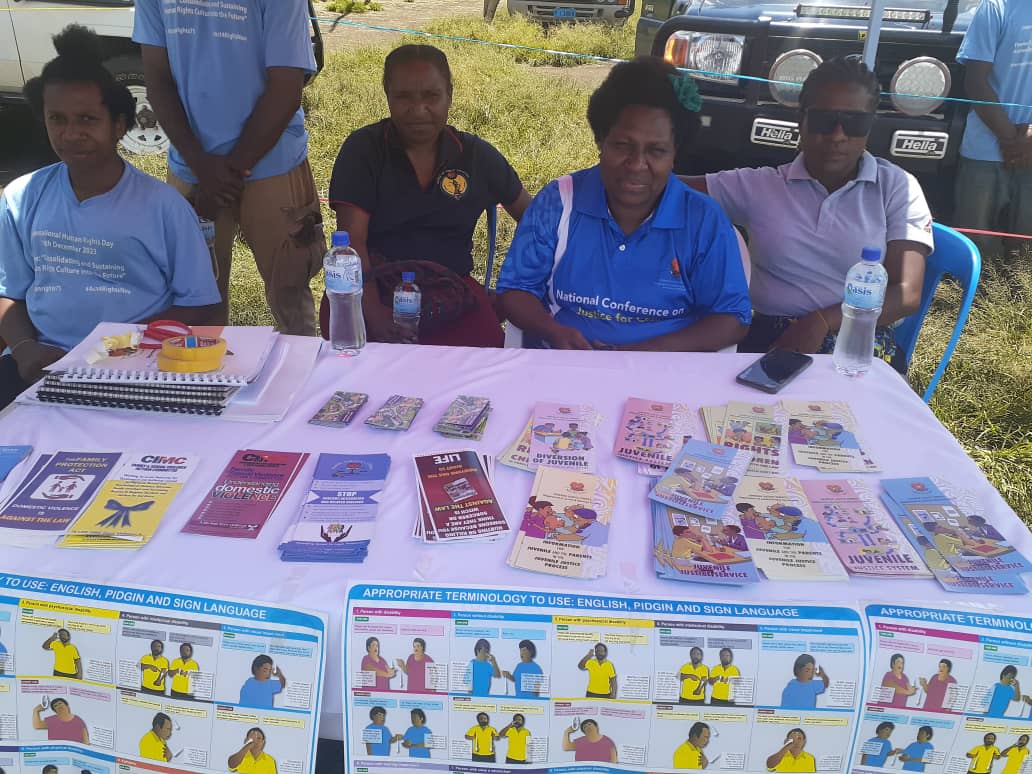 People manning a table with pamphlets and posters about gender-based violence.