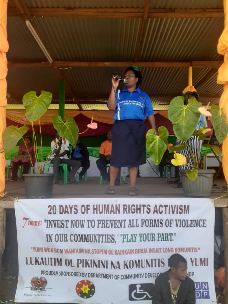 A woman is holding a microphone on stage as she addresses a crowd.