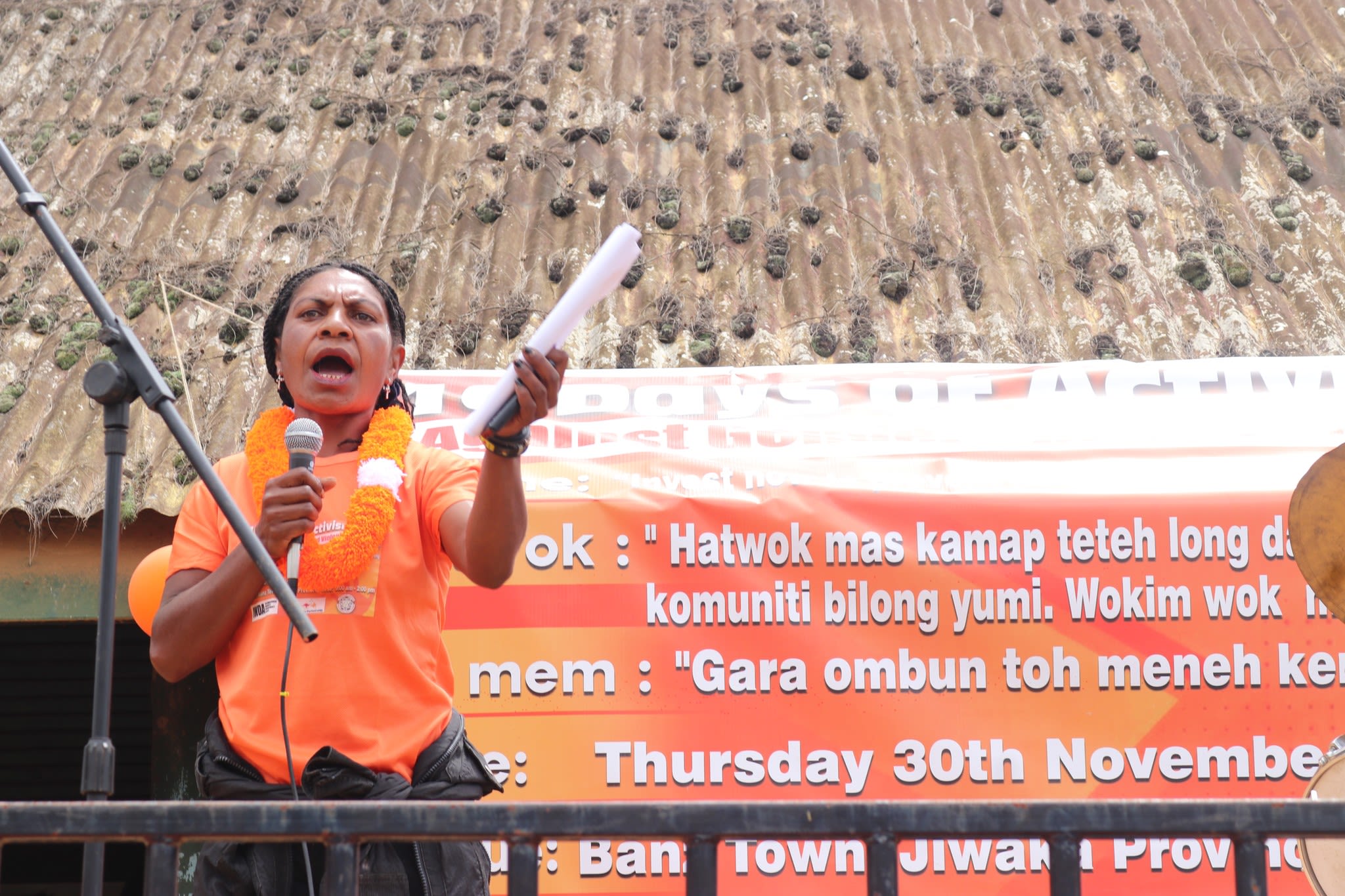 A woman is standing on stage as she speaks into a microphone to the crowd.