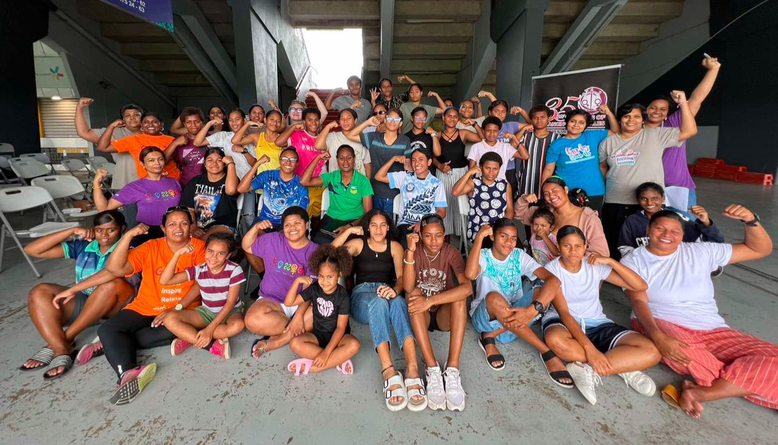 Participants at FWRM's intergenerational panel posing together with their arms raised.
