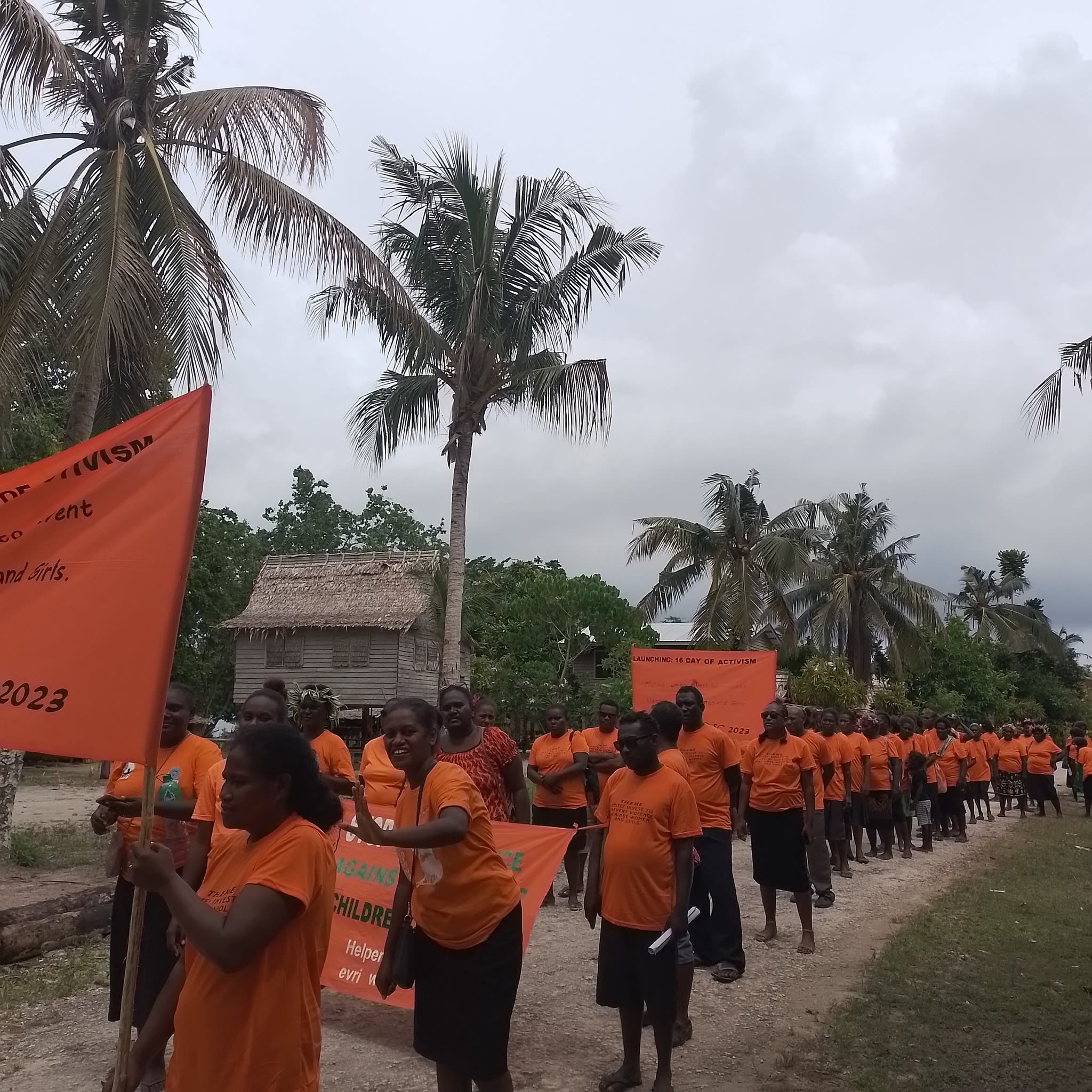 A crowd wearing orange t-shirts march through the streets of Gizo Town.