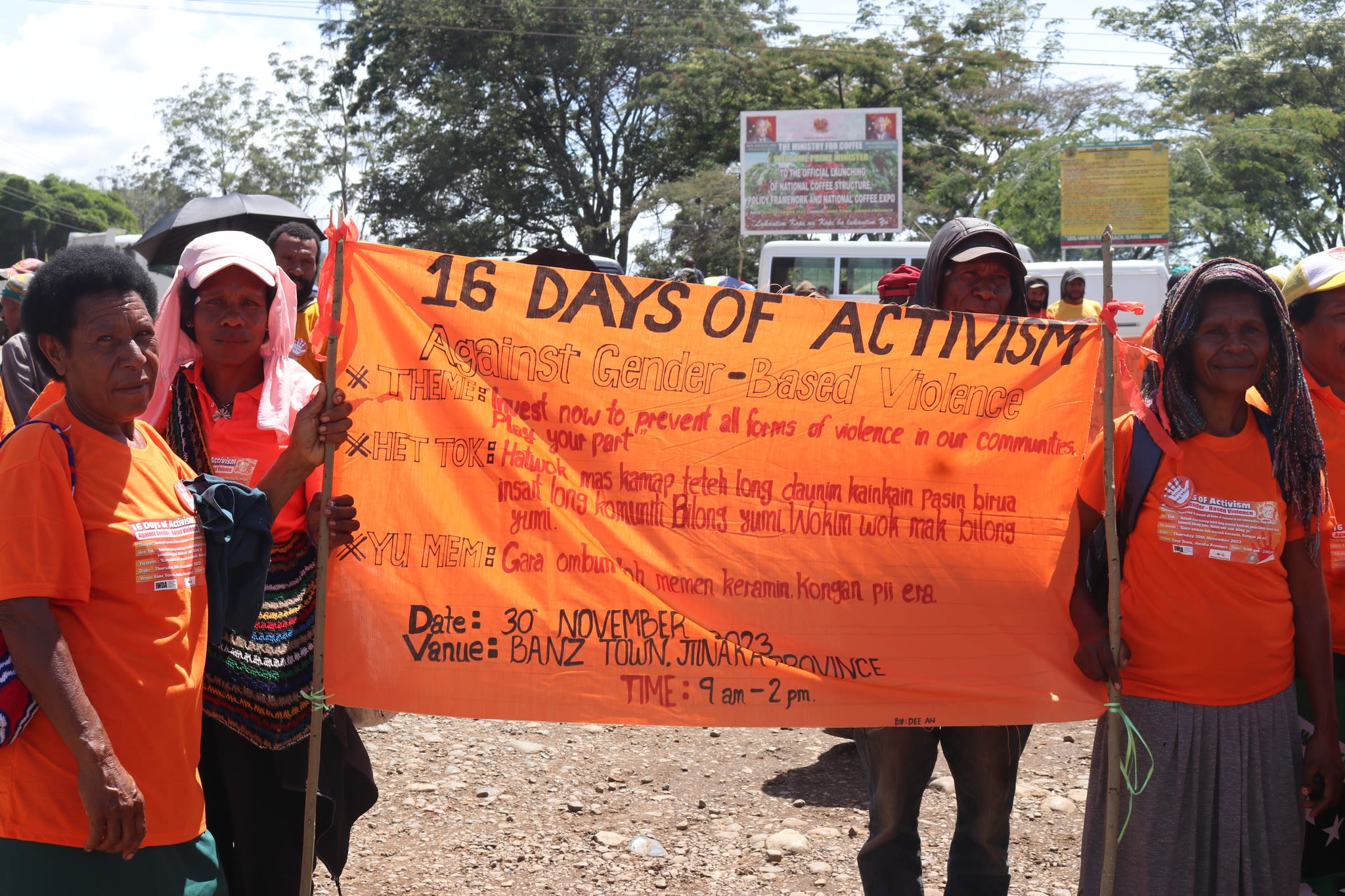 A group of women in orange shirts holding up a 16 Days banner.