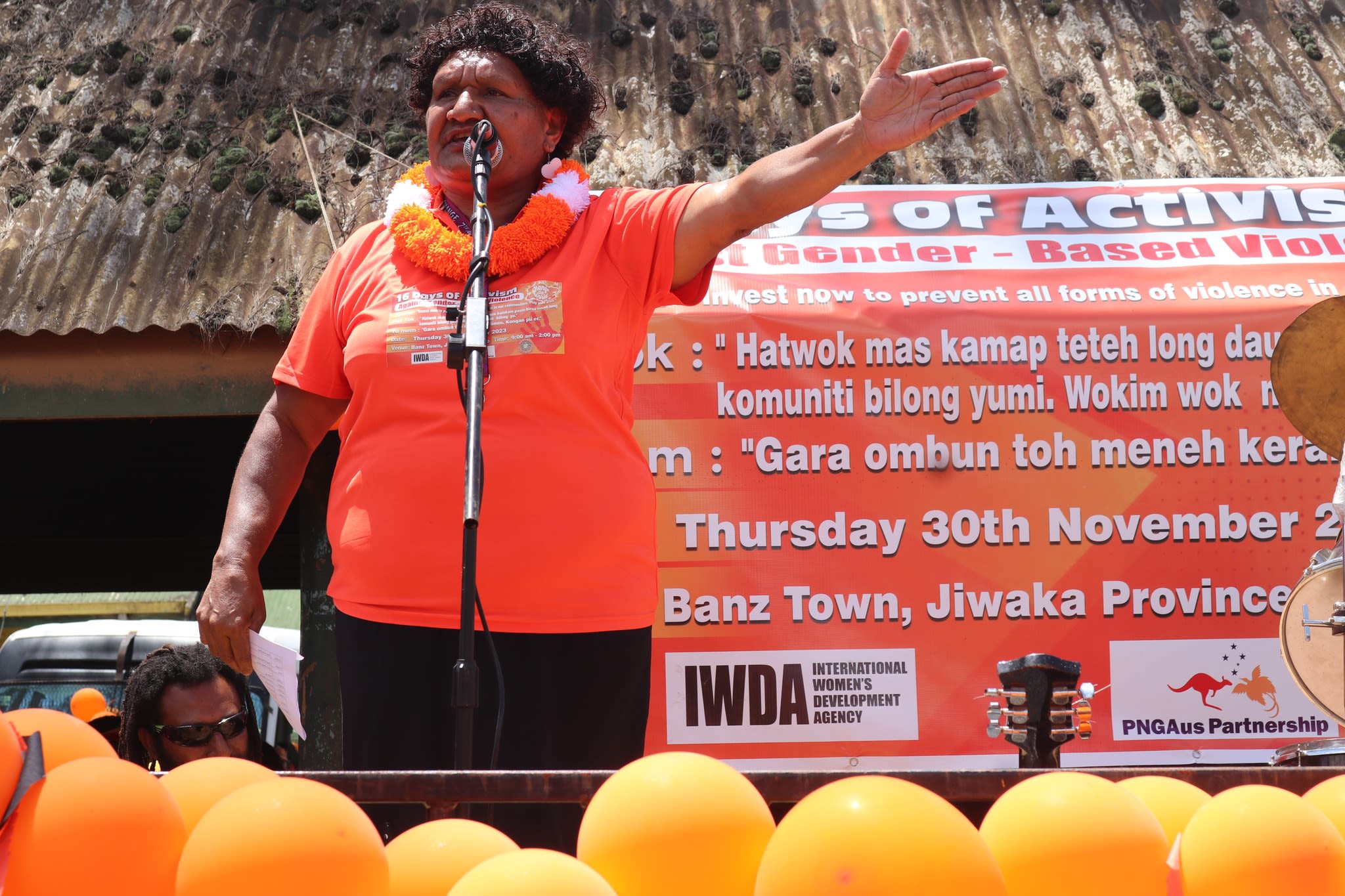 A woman is standing on stage as she speaks into a microphone to the crowd.