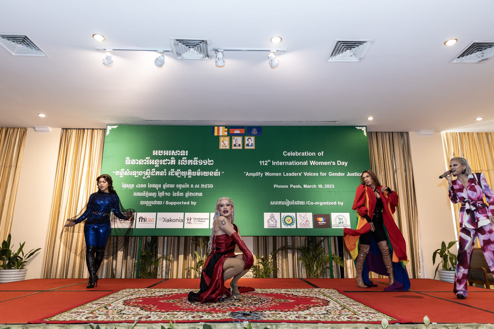 A group of performers on stage dancing and singing. Behind them is the 'Amplify Women Leaders' Voices for Gender Justice.